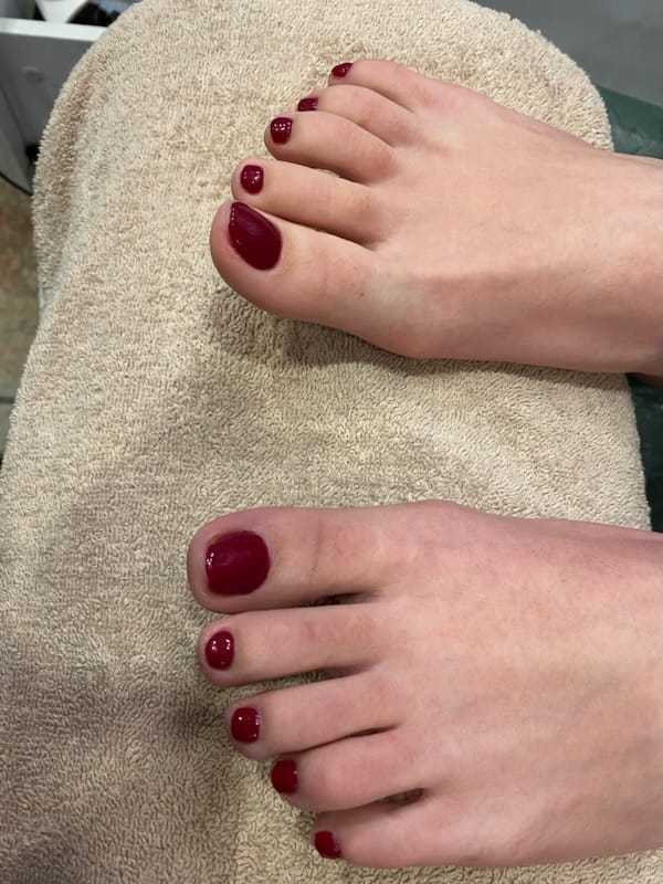 Freshly pedicured feet with dark red nail polish on a towel.