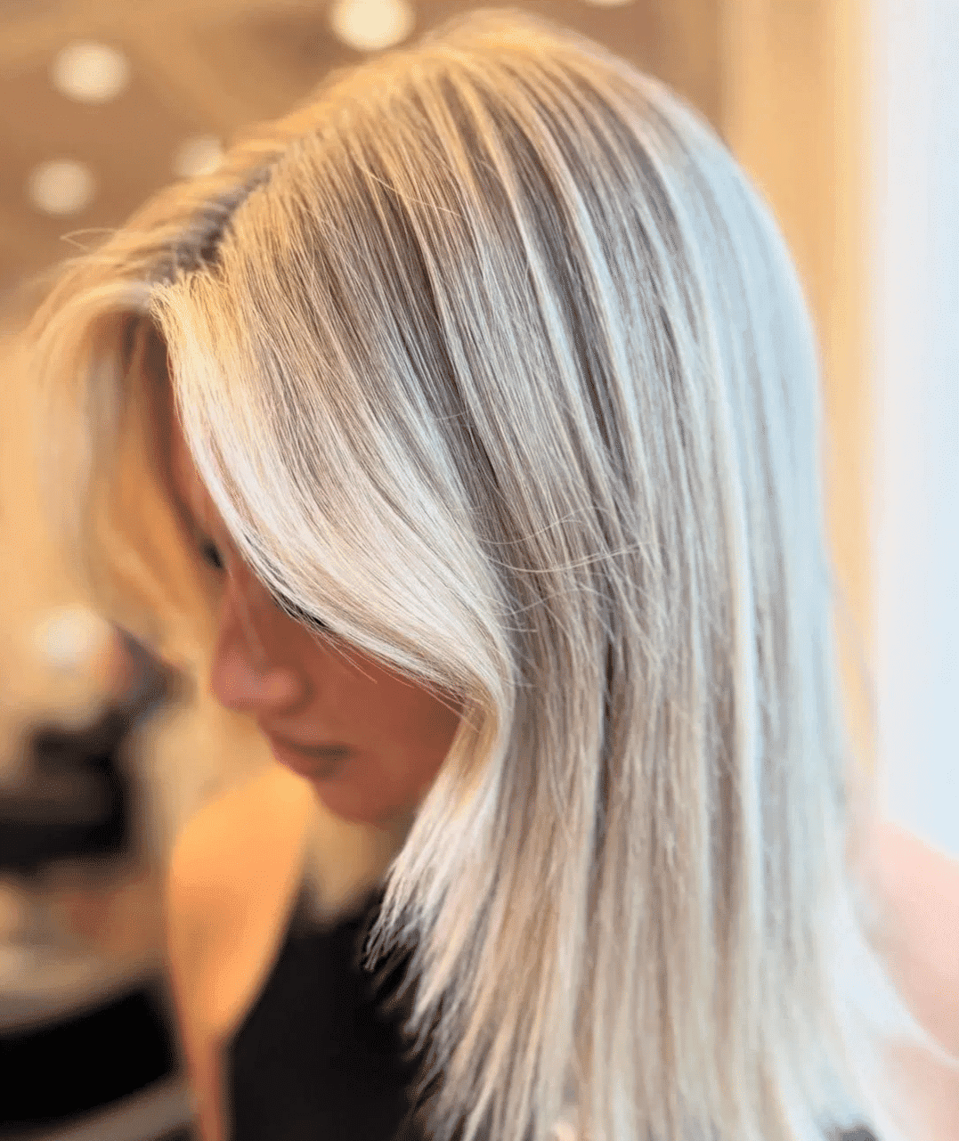 Blonde-haired person with a stylish, straight haircut at a salon.