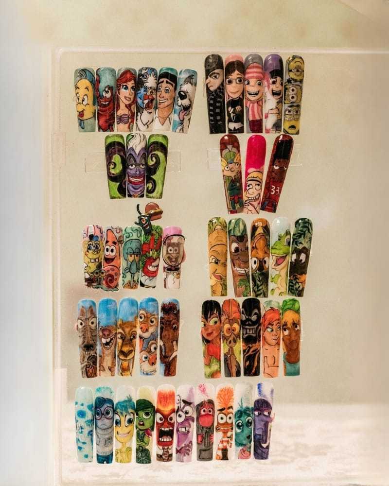 Colorful cartoon-themed nail art displayed on transparent stands.