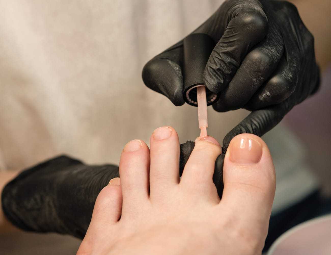 Person applying nail polish to toenails in a nail salon setting.