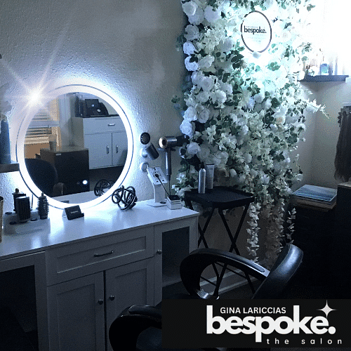 Salon station with illuminated mirror, tools, and floral wall decor. Text: "Bespoke: the salon.