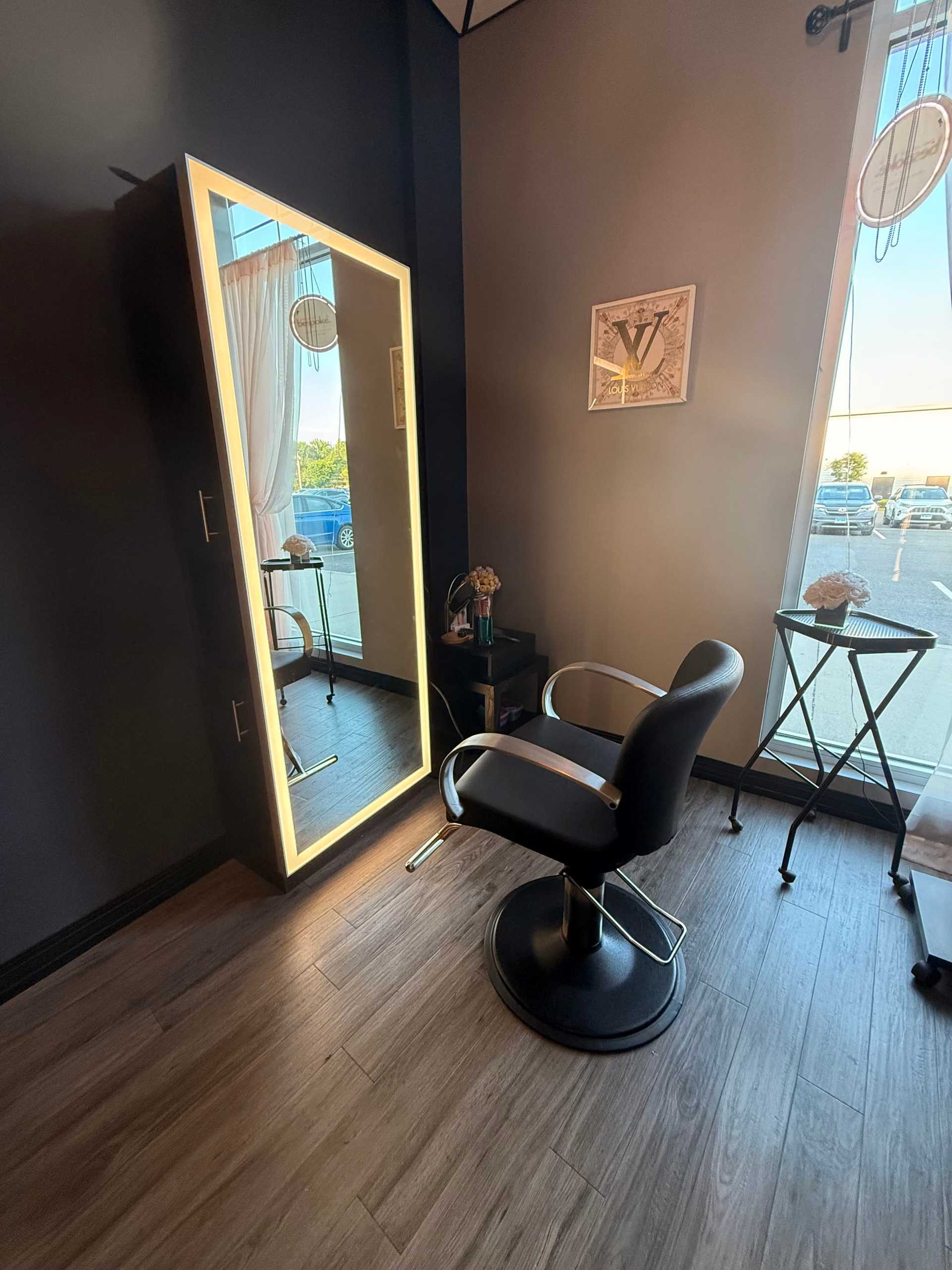 Modern salon chair and illuminated mirror in a stylish, sunlit space.