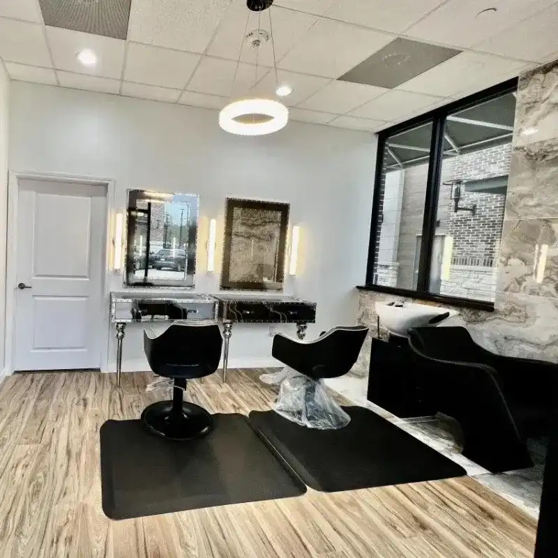 Modern hair salon interior with styling chairs, mirrors, and a wash basin.