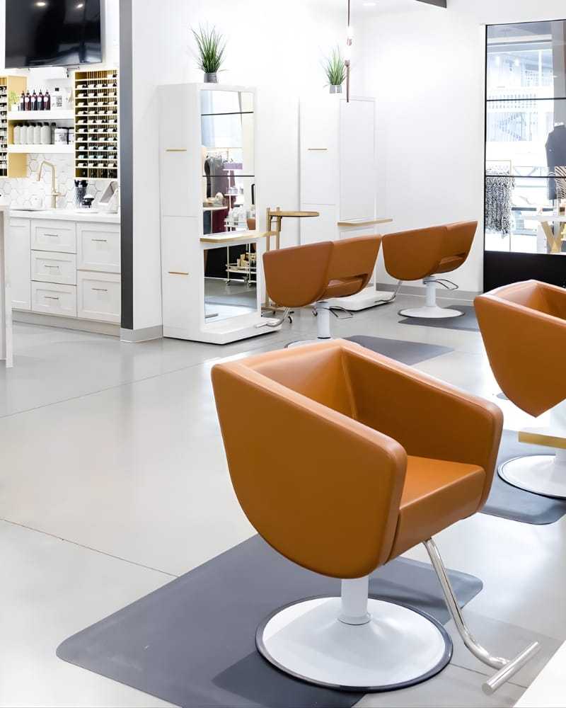 Modern salon interior with orange chairs and styling stations.