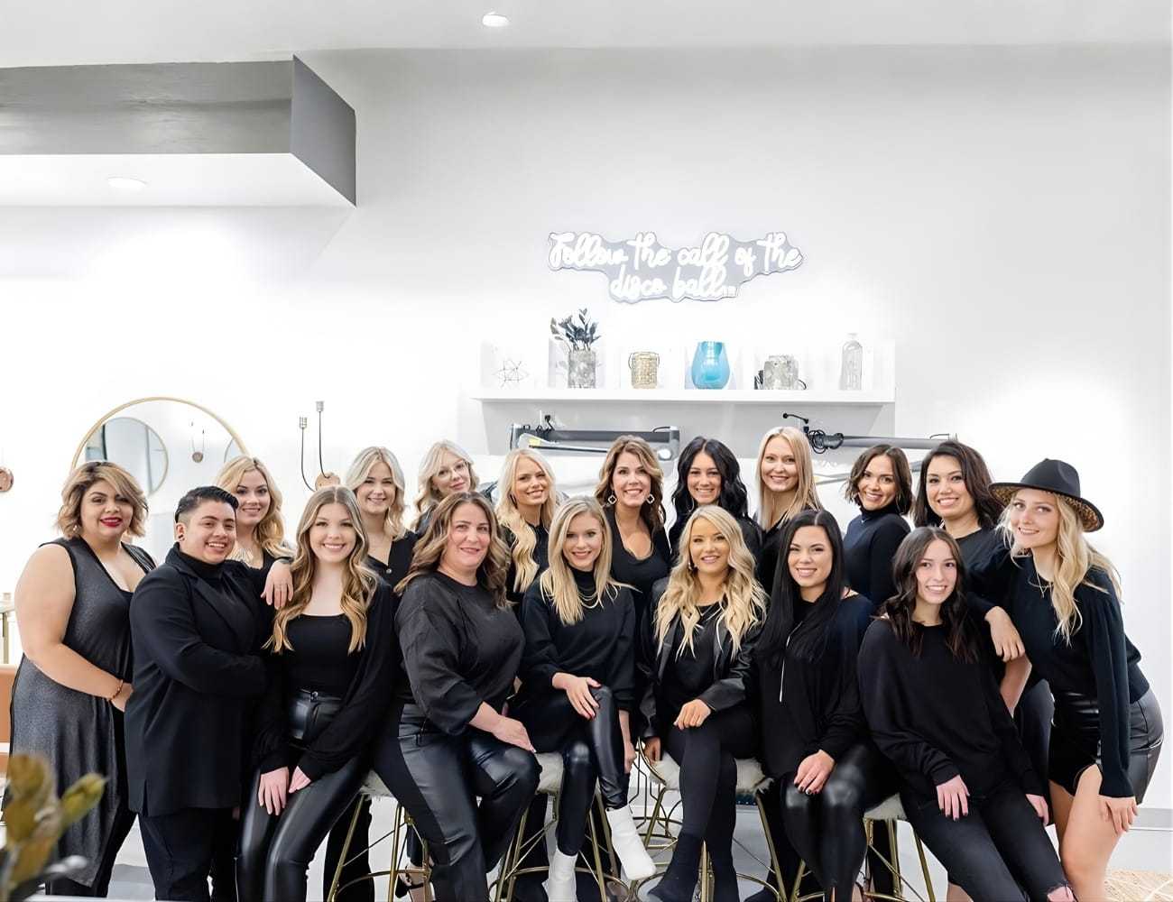 Group of people dressed in black, posing together in a stylish, modern room.