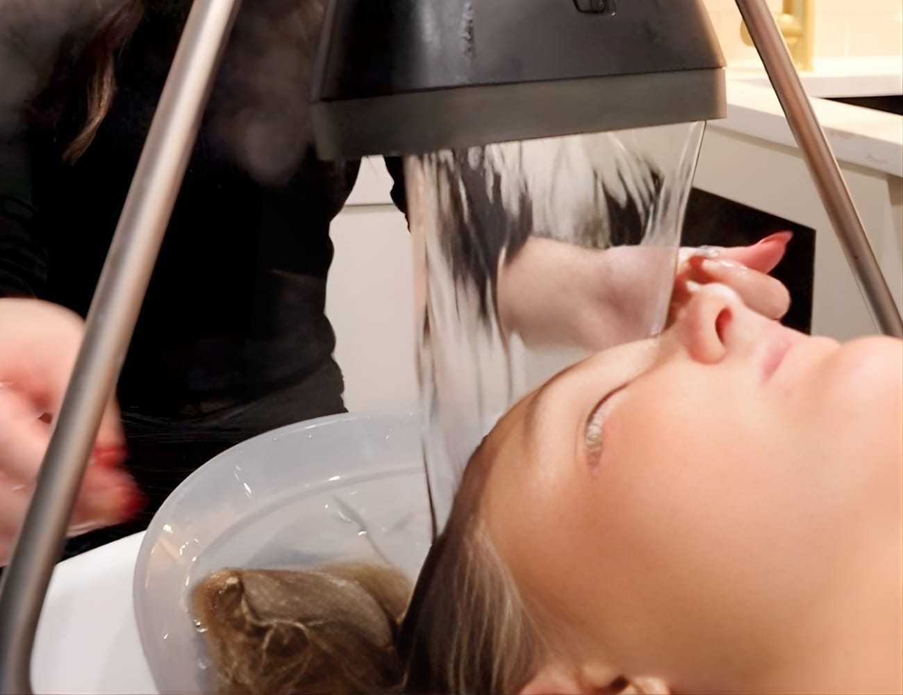 Spa treatment with steam over a person's face, hands adjusting the device.