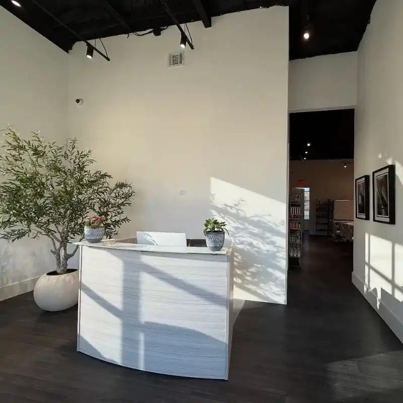 Modern reception area with a desk, potted plants, and minimalist decor.