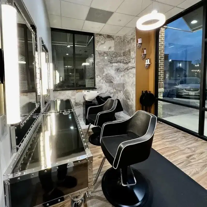 Salon interior with stylish black chairs, mirrors, and modern lighting by large windows.