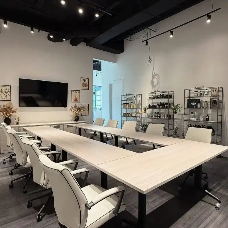Modern conference room with white chairs, U-shaped table, and shelves displaying decor.