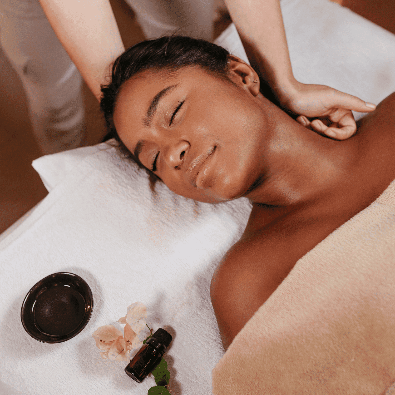 Woman receiving a relaxing neck massage at a spa, surrounded by oils and flowers.