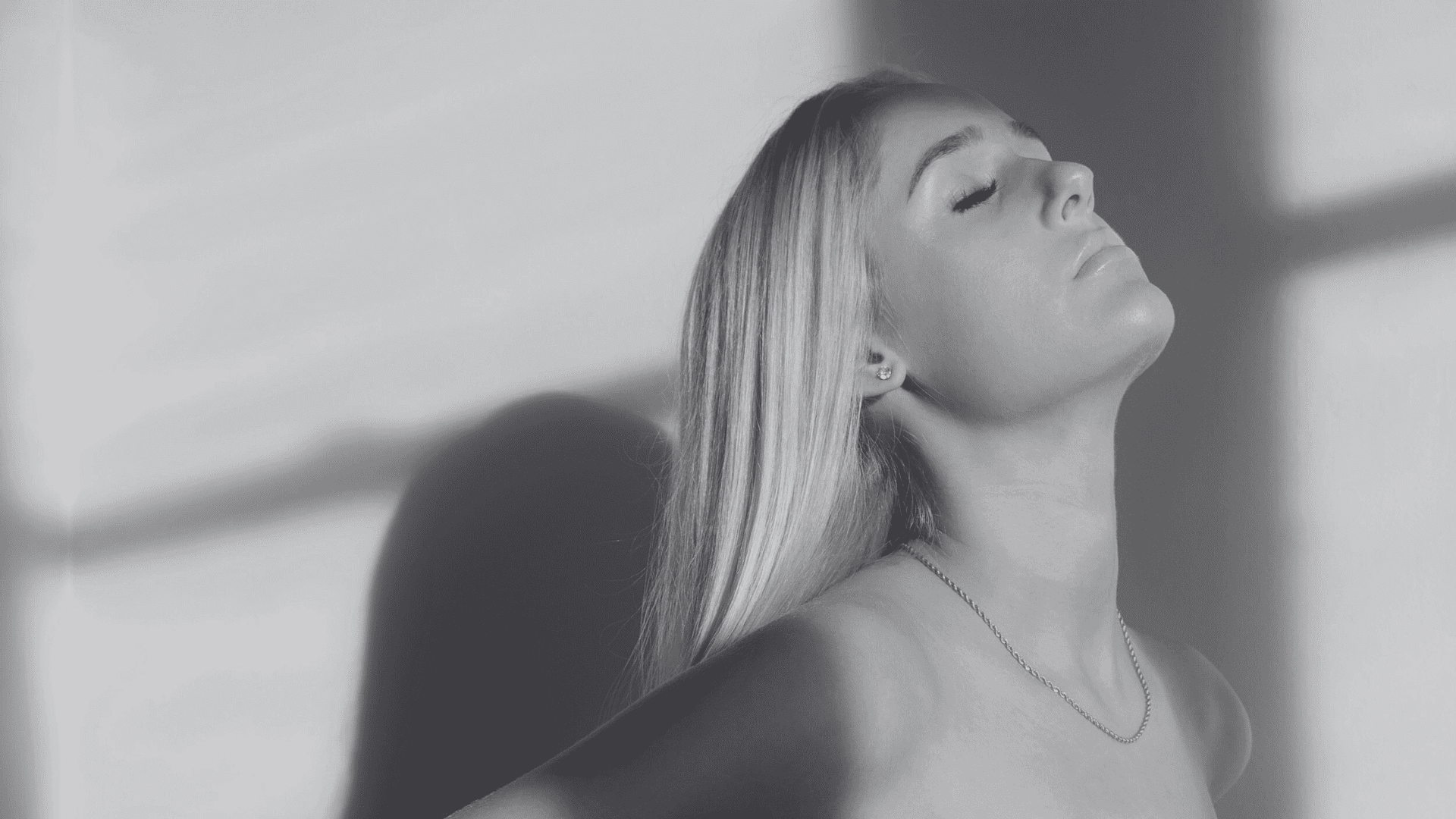 Shadowed profile of a woman, eyes closed, in serene light.