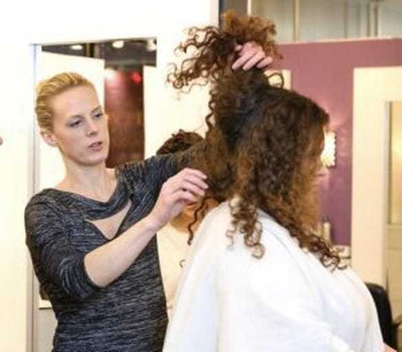 Stylist adjusting client's curly hair in a salon setting.