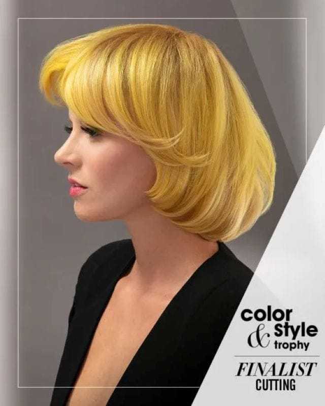 Woman with short yellow hair, black top; finalist in cutting category at hair styling event.