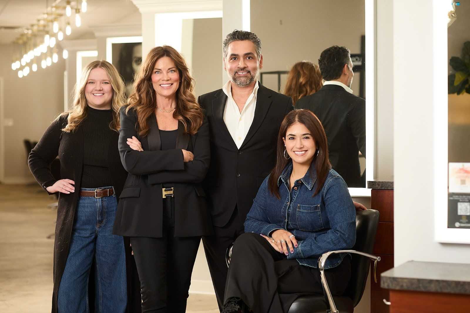 Group of four people in a salon, smiling and posing together.