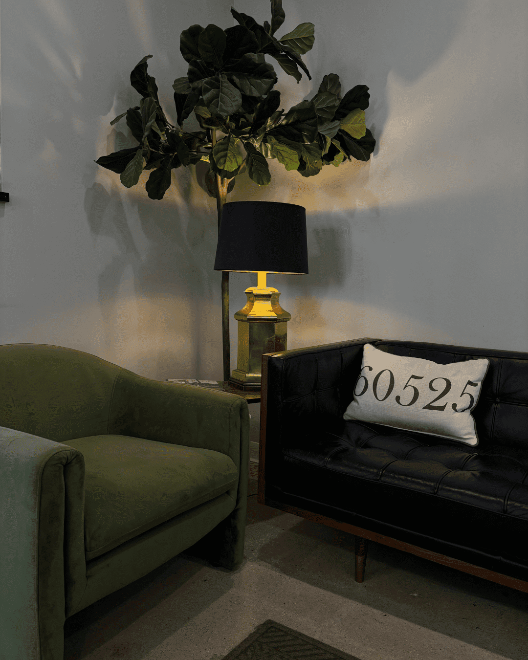Cozy living area with green chair, black couch, and lamp. Pillow shows "80525".
