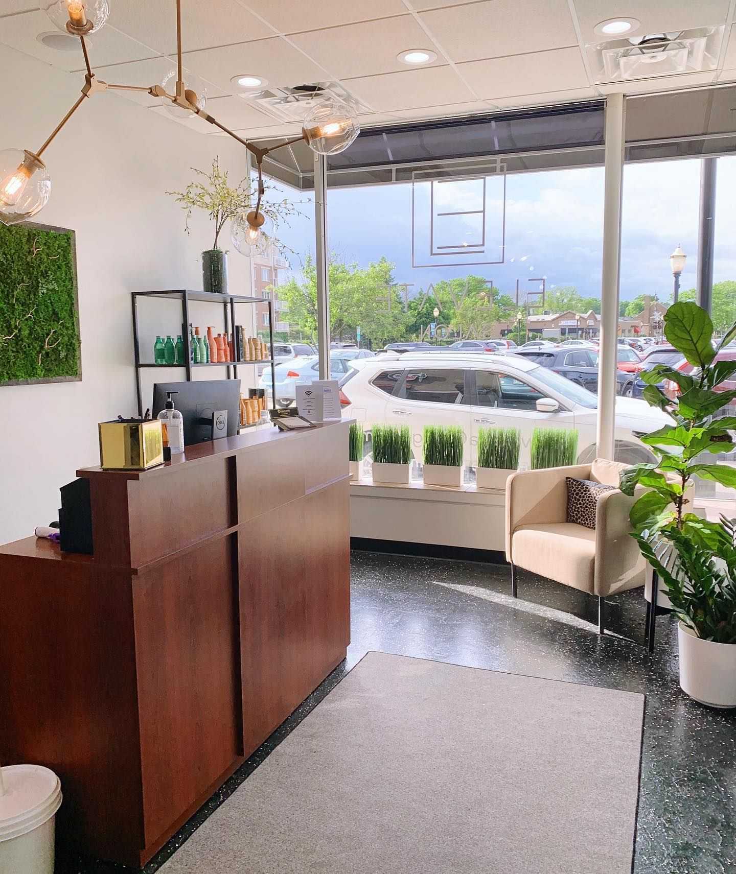 Bright lobby with modern decor and large window overlooking parked cars outside.