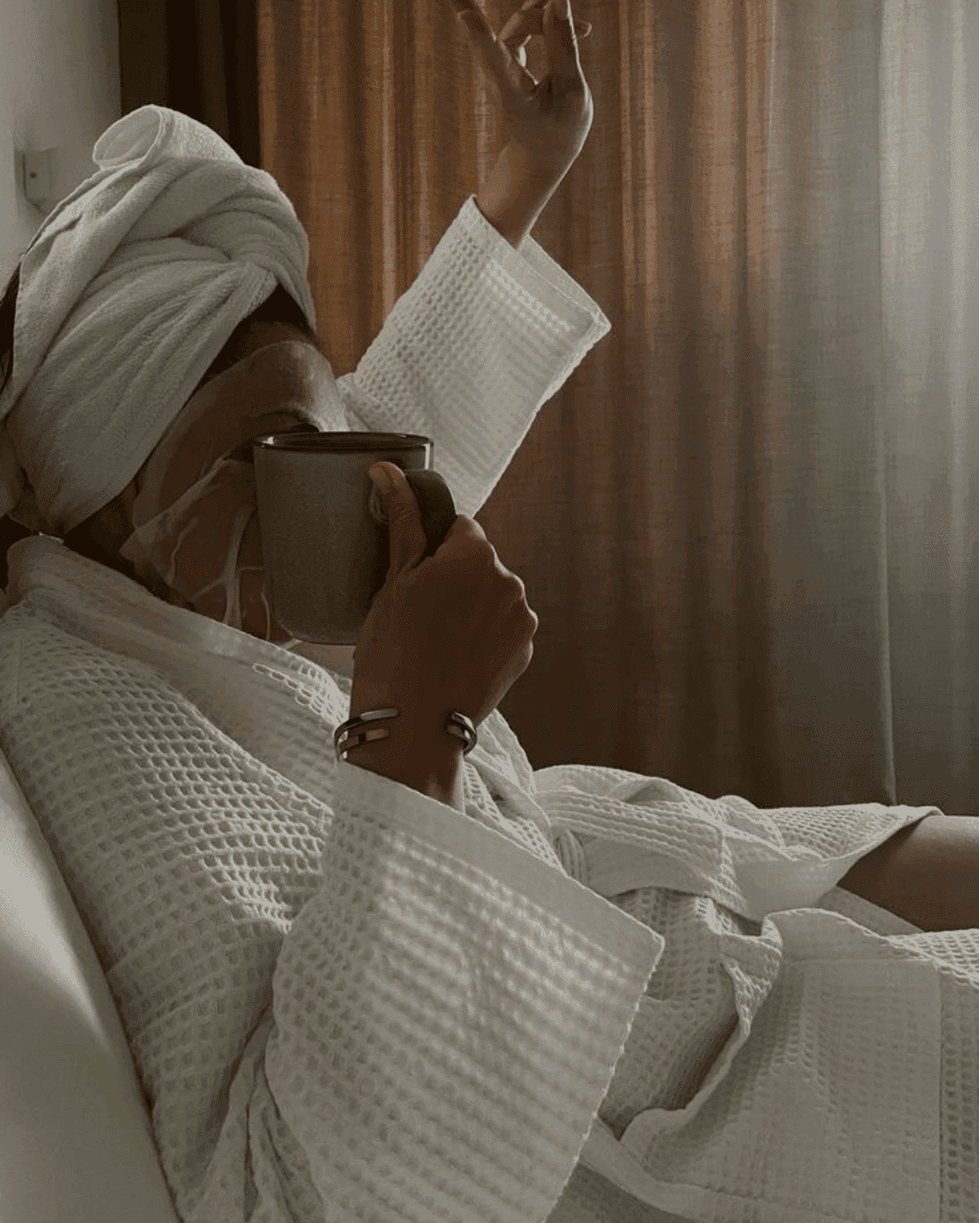 Relaxing in a robe with a face mask and hot drink in hand.