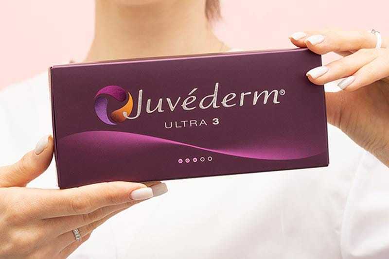 Hands holding a Juvéderm Ultra 3 box with a pink background.