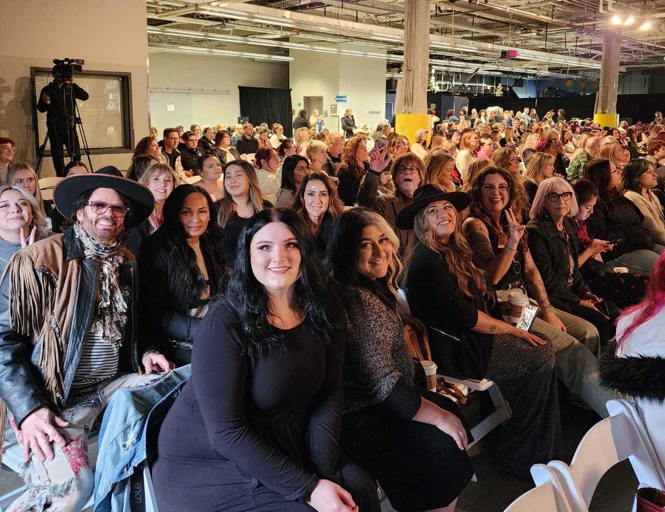 Audience seated at a fashion show, smiling and engaging with the event.