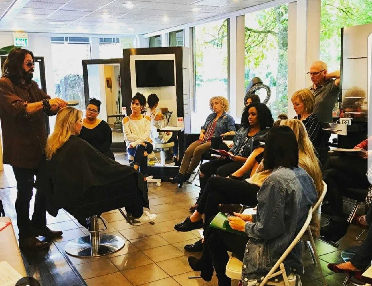 Hair stylist demonstrating techniques to a group in a salon setting.