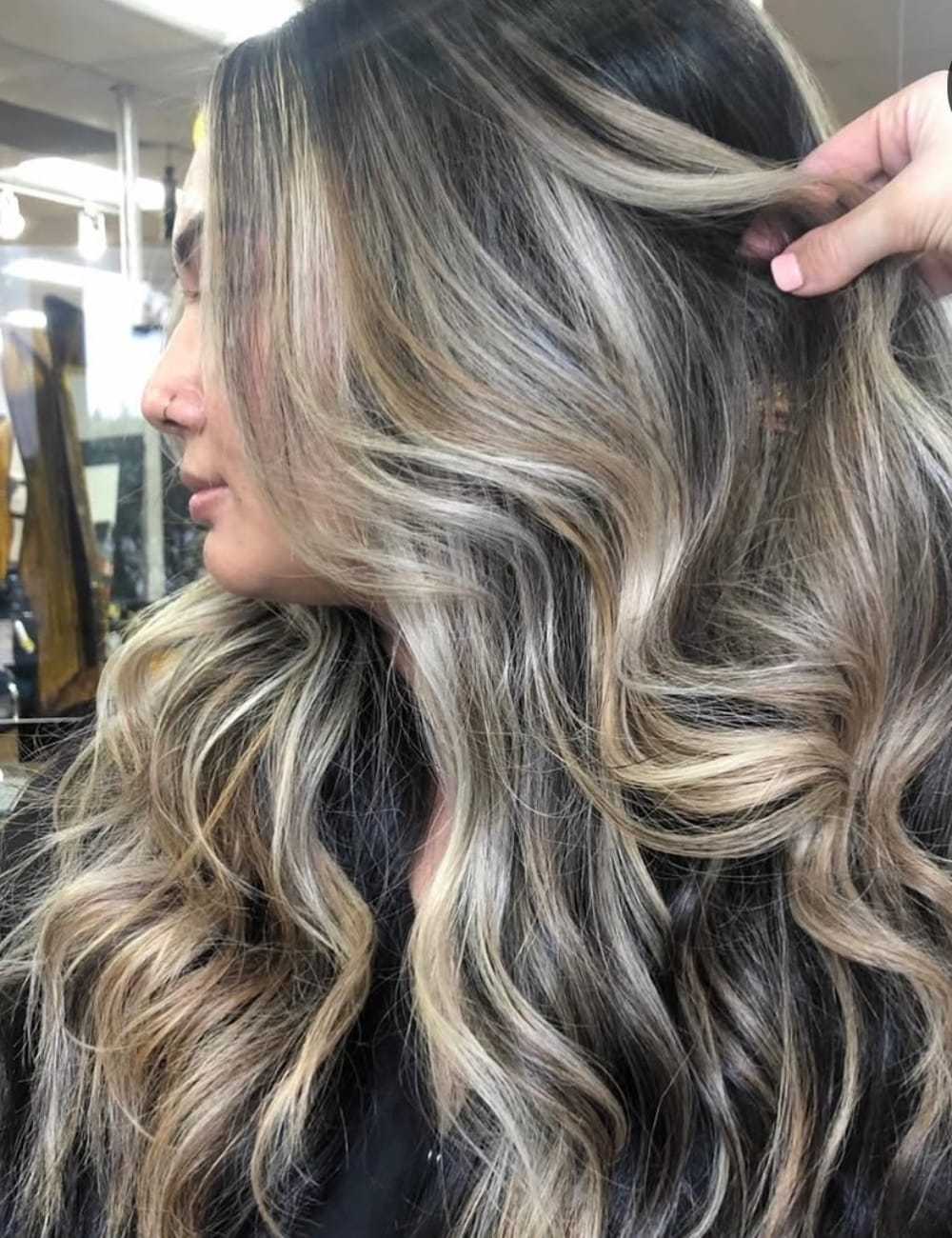 Wavy hair with blonde and brown highlights styled in a salon.