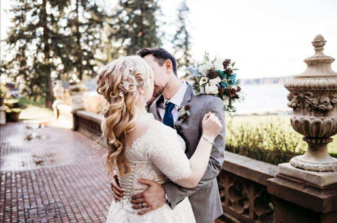 Bride and groom sharing a kiss outdoors with scenic background.