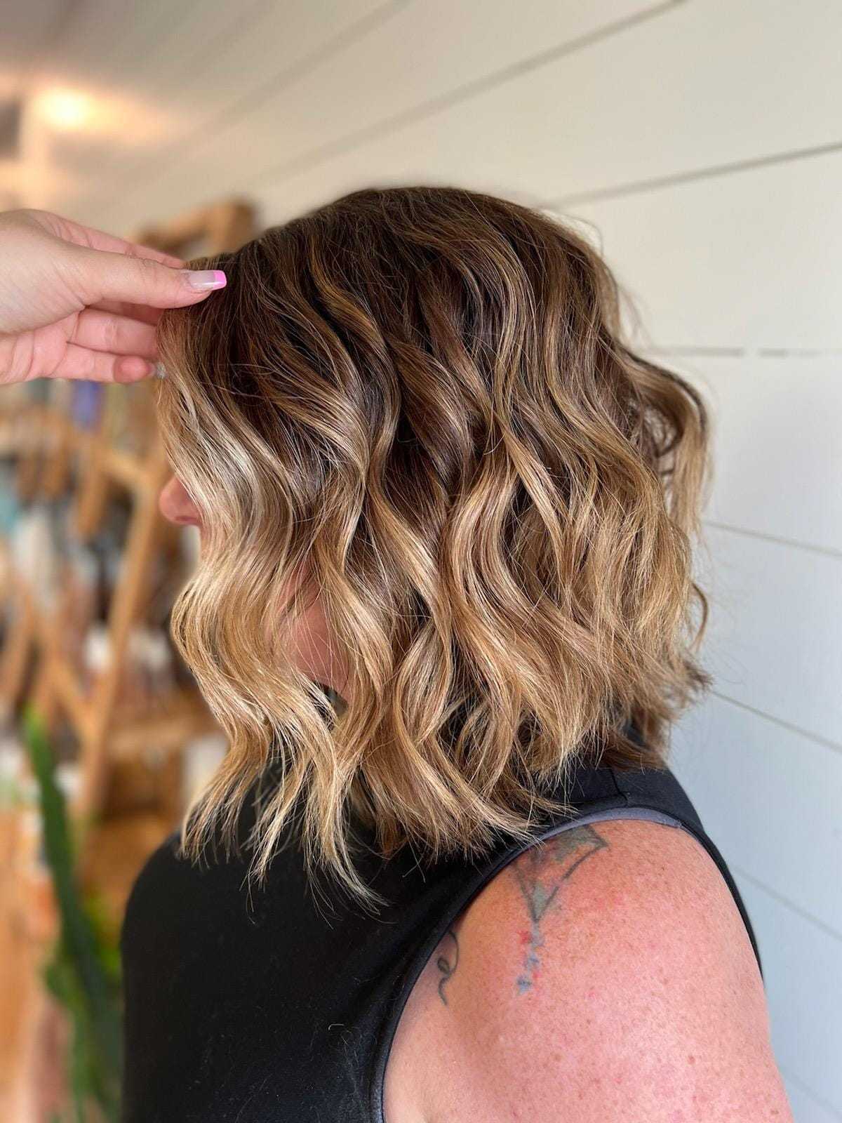 Wavy brunette bob with blonde highlights in a salon setting.