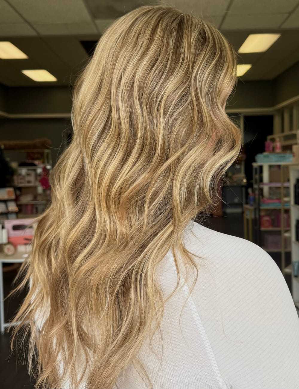 Wavy blonde hair styled in loose curls, photographed in a salon setting.