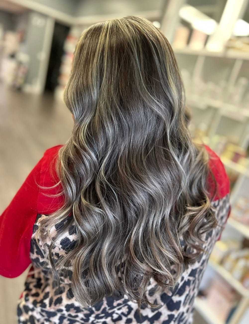 Wavy, ash blonde hair flowing down back, person wearing red and leopard print top.
