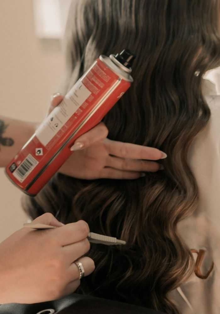 Hair being styled with a curling iron and hairspray.