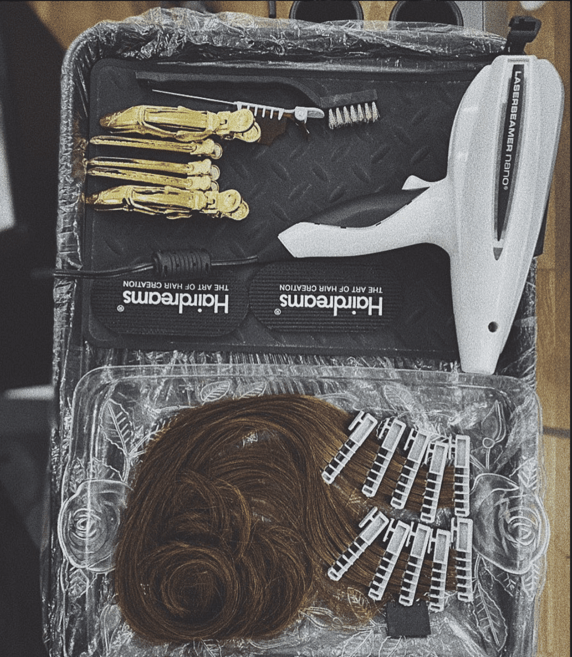 Hair styling tools and accessories, including extensions, clips, and styling device on a tray.
