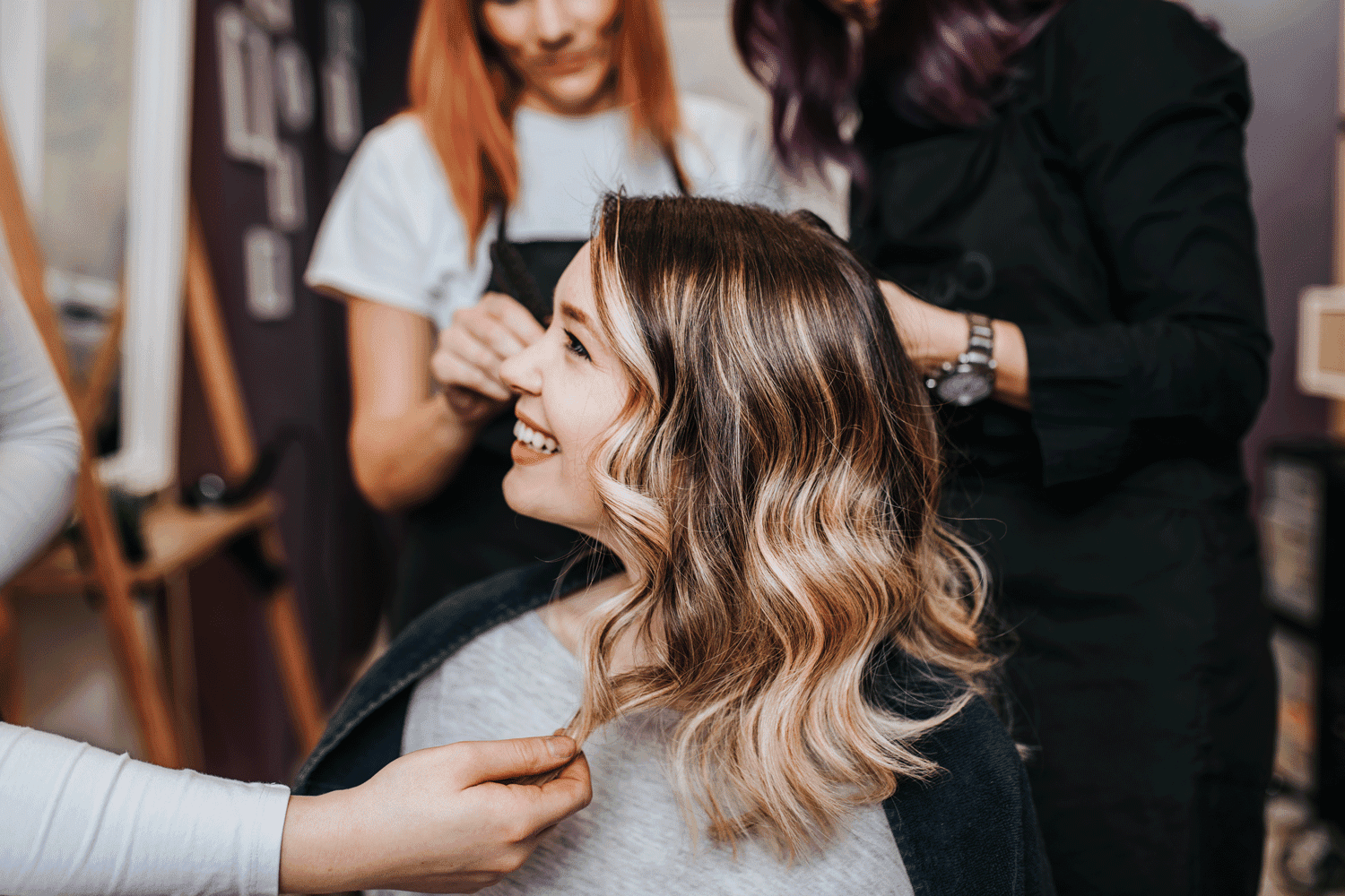 Woman getting hairstyle with hand touch in salon setting.