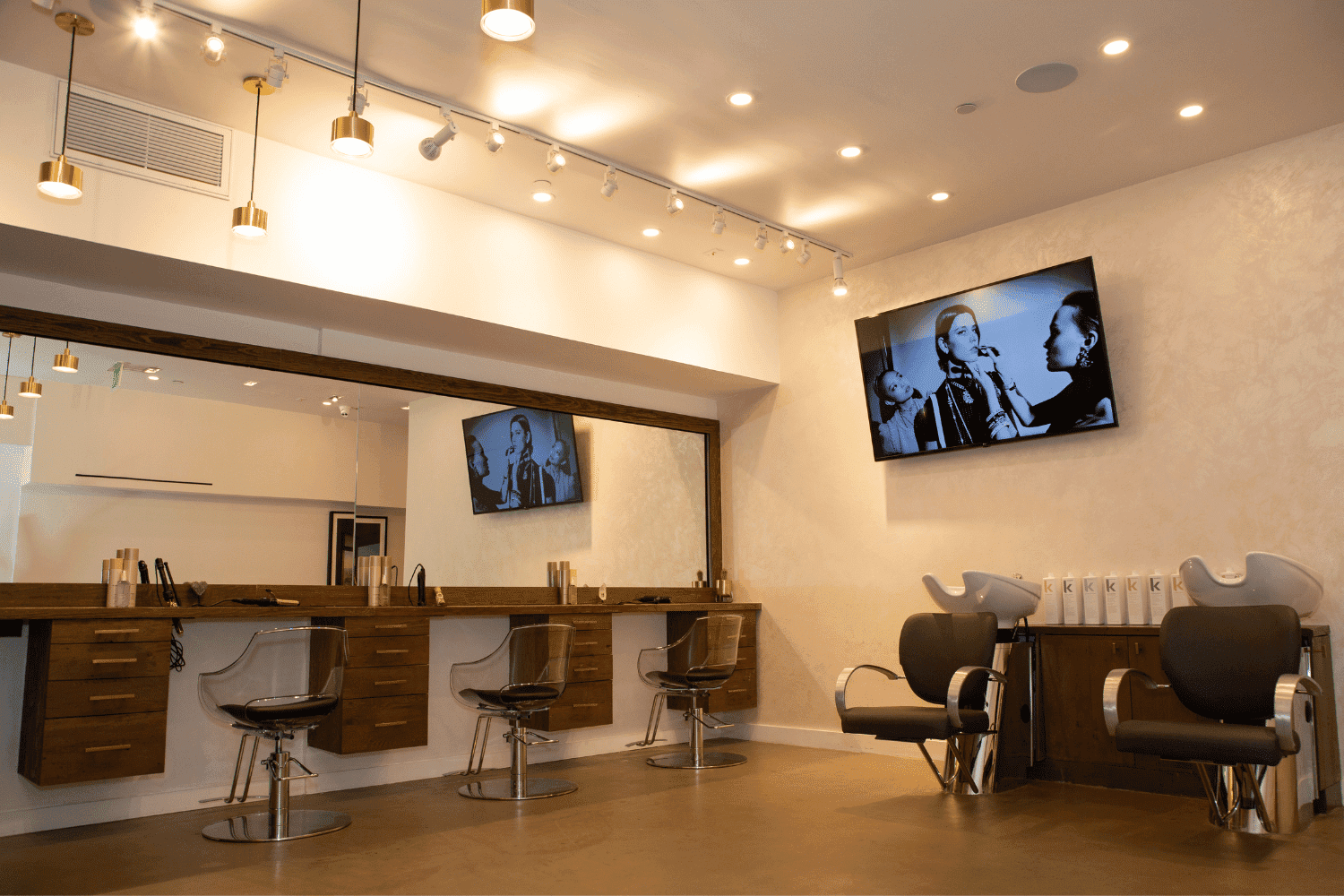 Modern hair salon interior with styling chairs, large mirrors, and a black-and-white photo on the wall.
