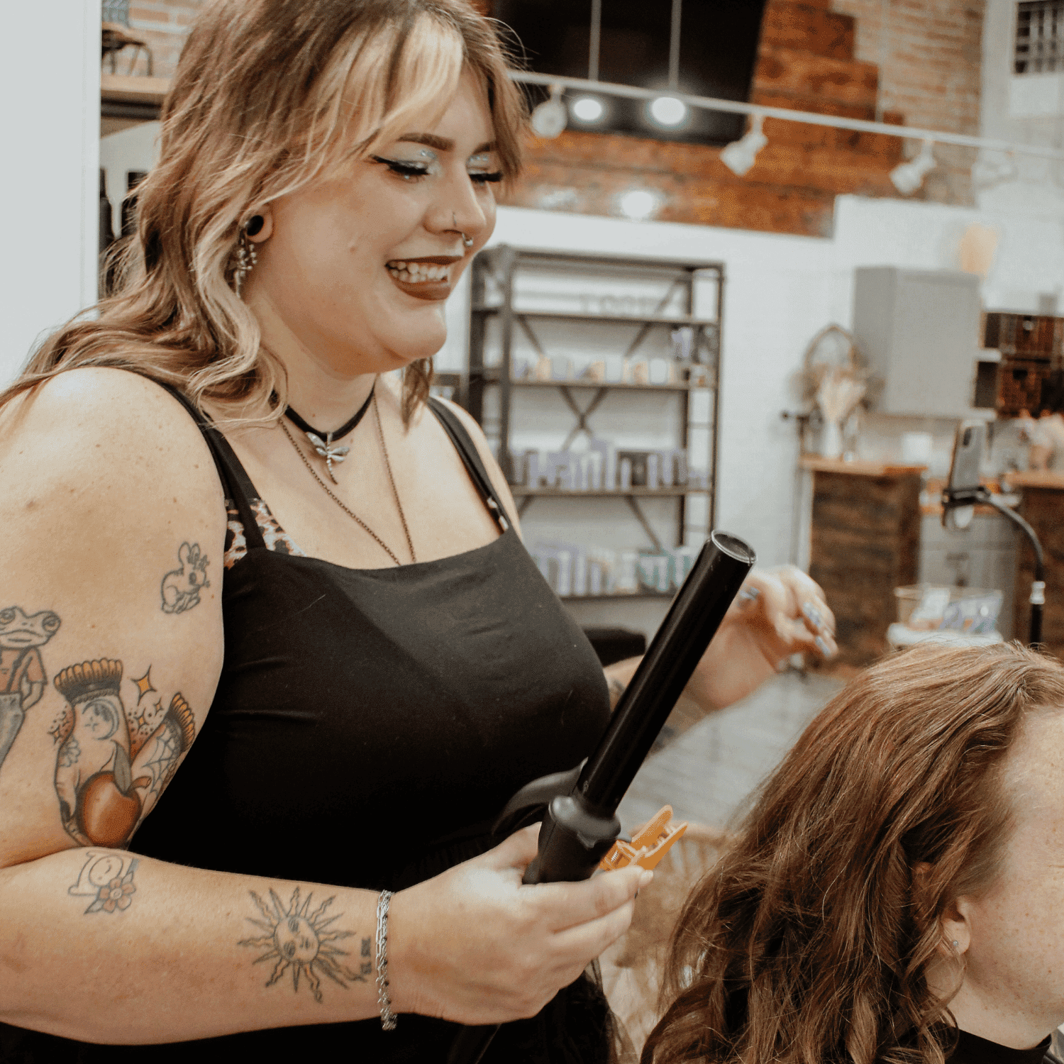 Hair stylist curling a client's hair in a salon.