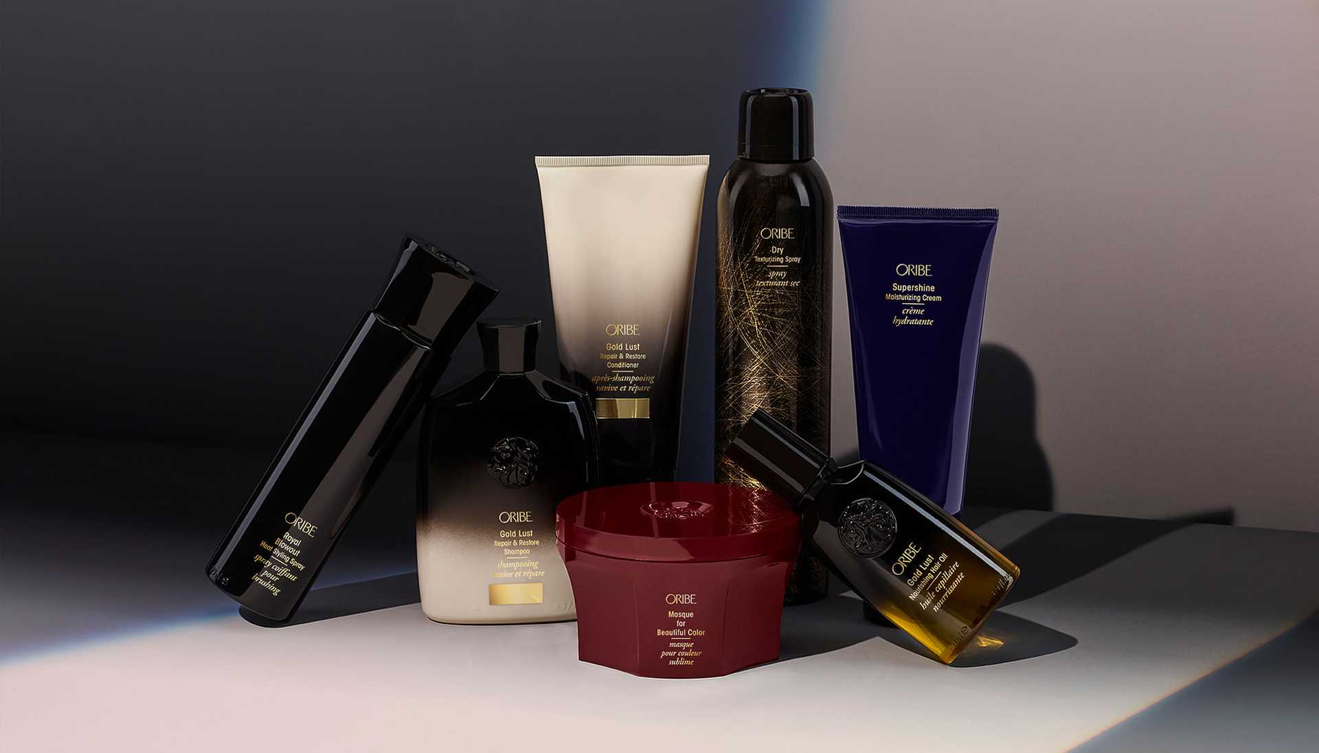 Haircare product collection on a dark background, featuring sprays, lotions, and creams.