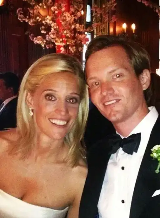Wedding couple smiling at the camera in a warmly lit venue.