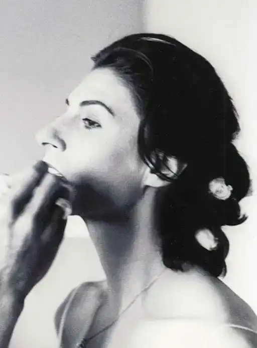 Bridal portrait of a woman with roses in her hair, applying makeup.