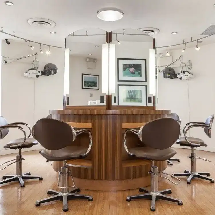 Modern salon with wooden styling stations and swivel chairs.