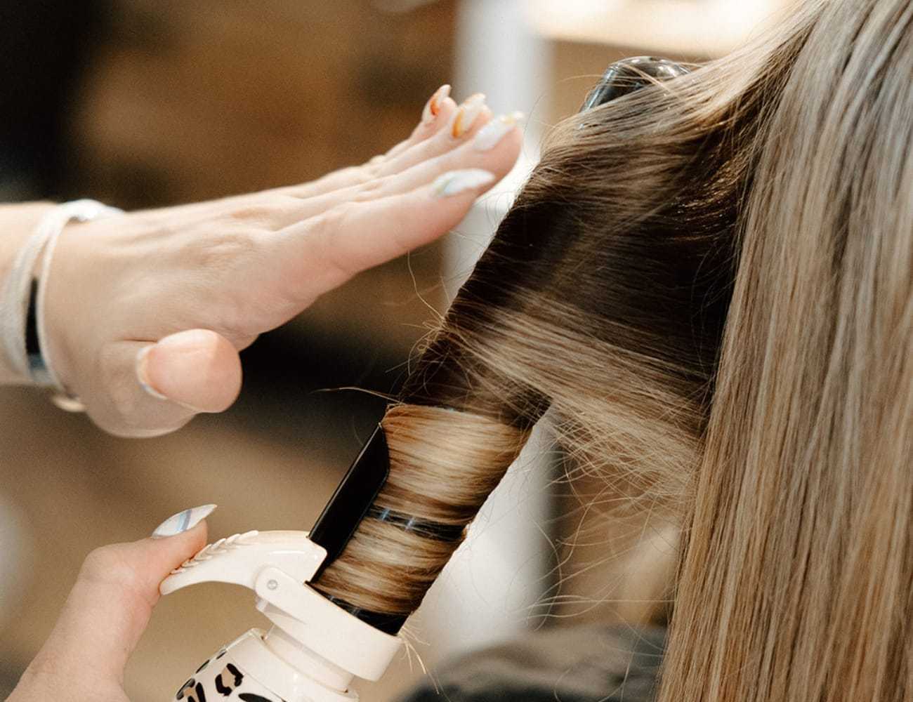Hair being styled with a curling iron, showcasing a professional hairstyling technique.