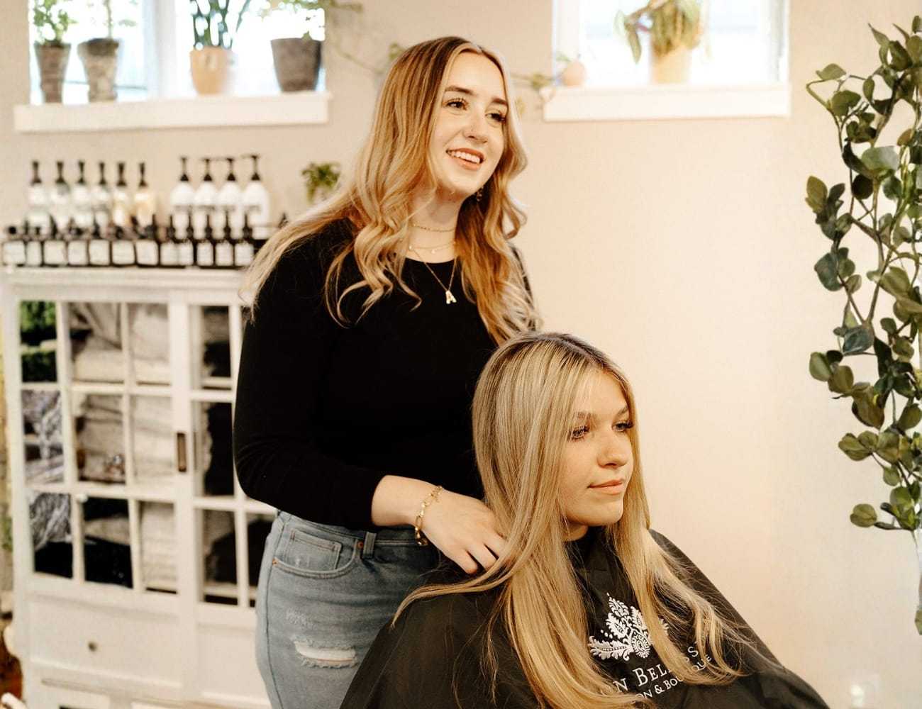 Hairstylist working on a client's hair in a bright, modern salon setting.