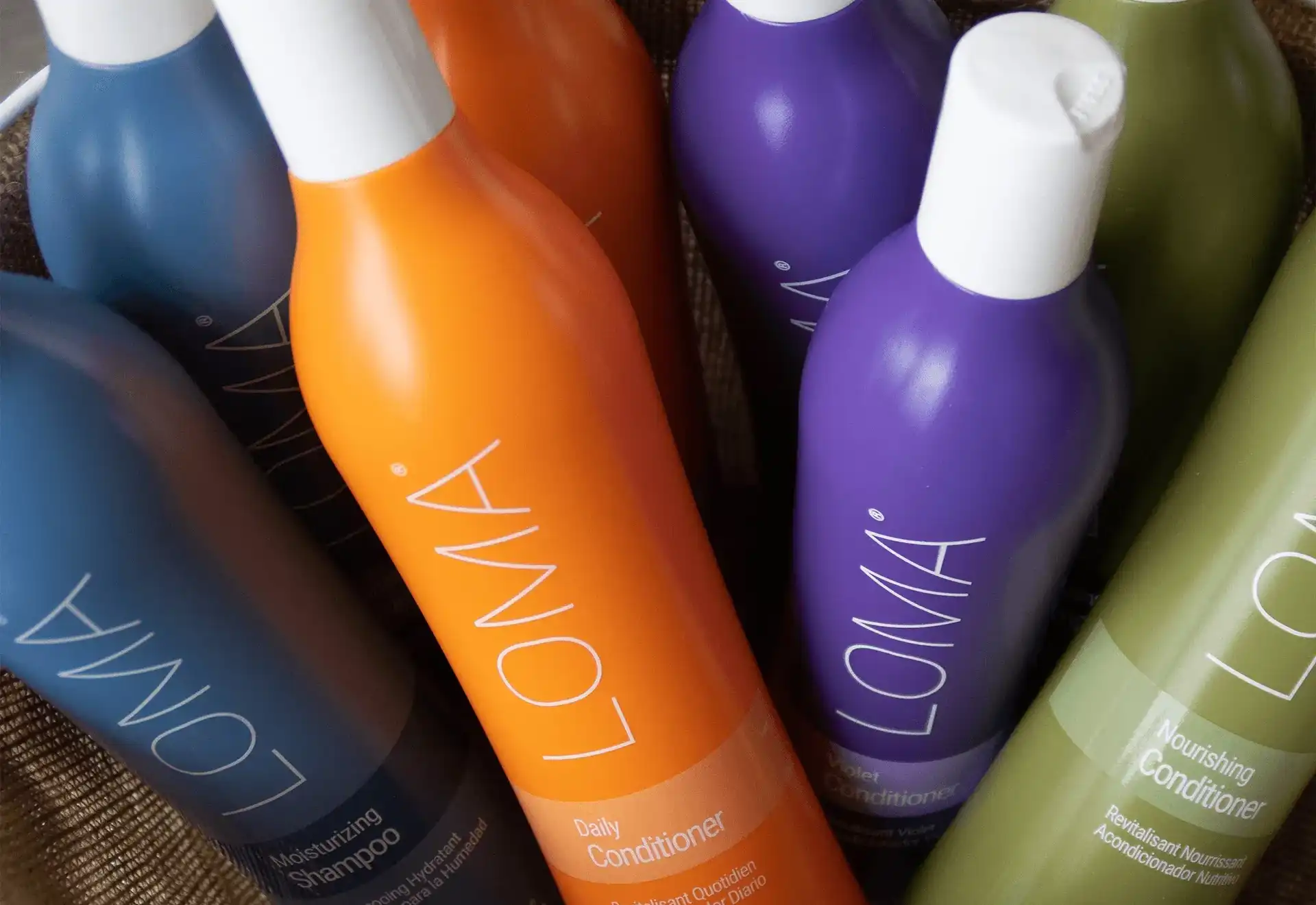 LOMA shampoo and conditioner bottles in different colors in a basket.