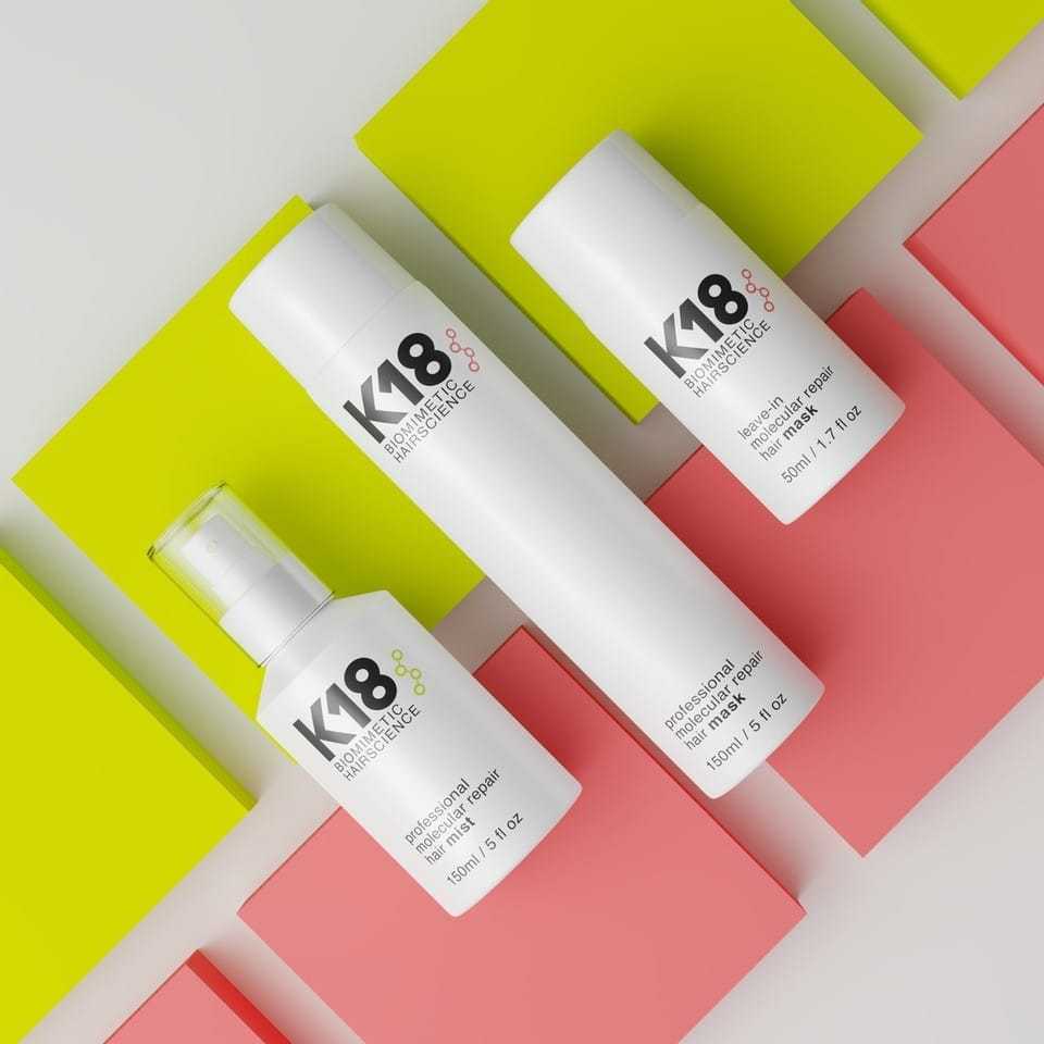 K18 hair care products on colorful geometric background.