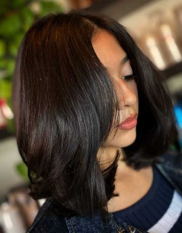 Young woman with dark, shoulder-length hair in a cozy setting.