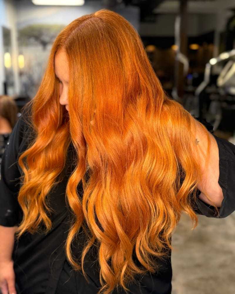 Long, wavy, vibrant orange hair styled in a salon setting.