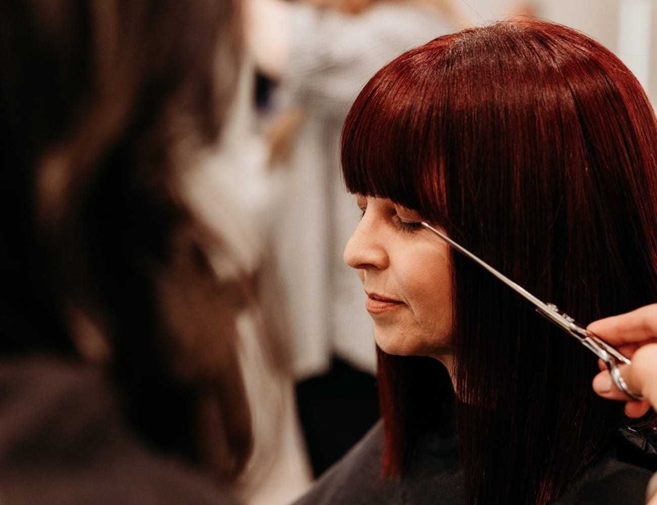 Woman with red hair getting a haircut at a salon.