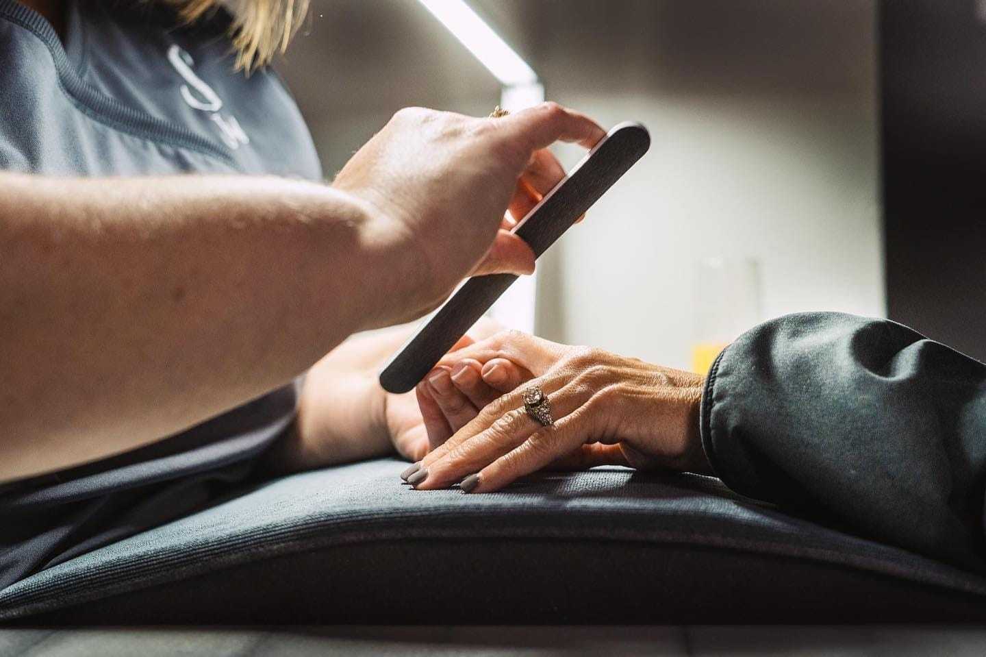 Hands getting a manicure with a nail file.