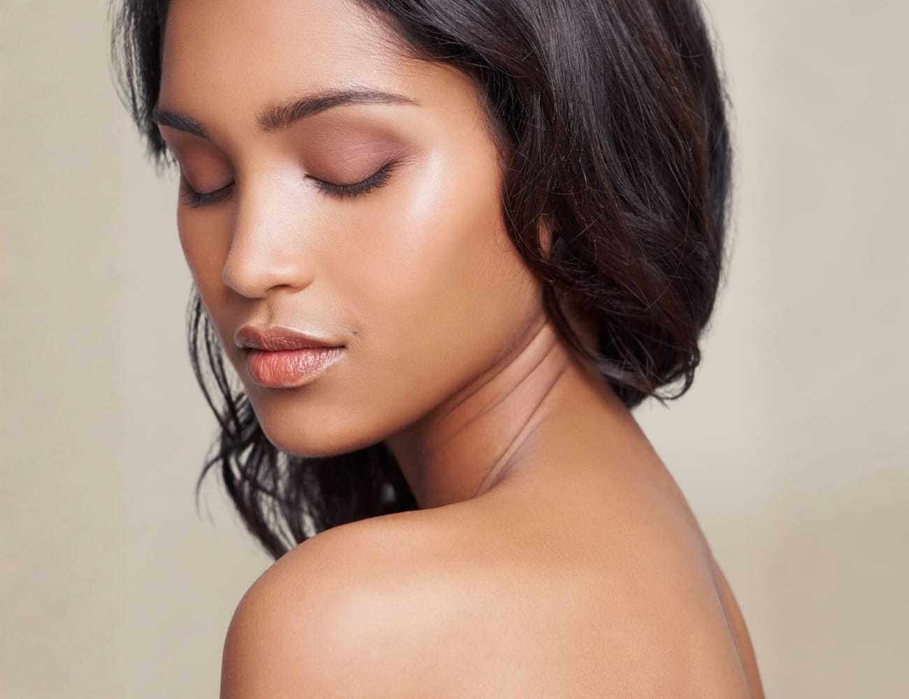 Woman with closed eyes, calm expression, bare shoulders, soft makeup, and smooth skin.