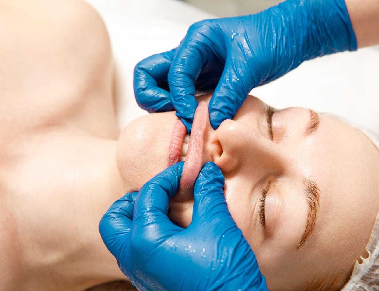 Facial massage performed on person wearing blue gloves.