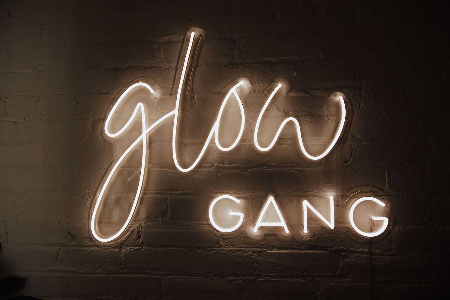 Neon sign on a brick wall reads "Glow Gang".