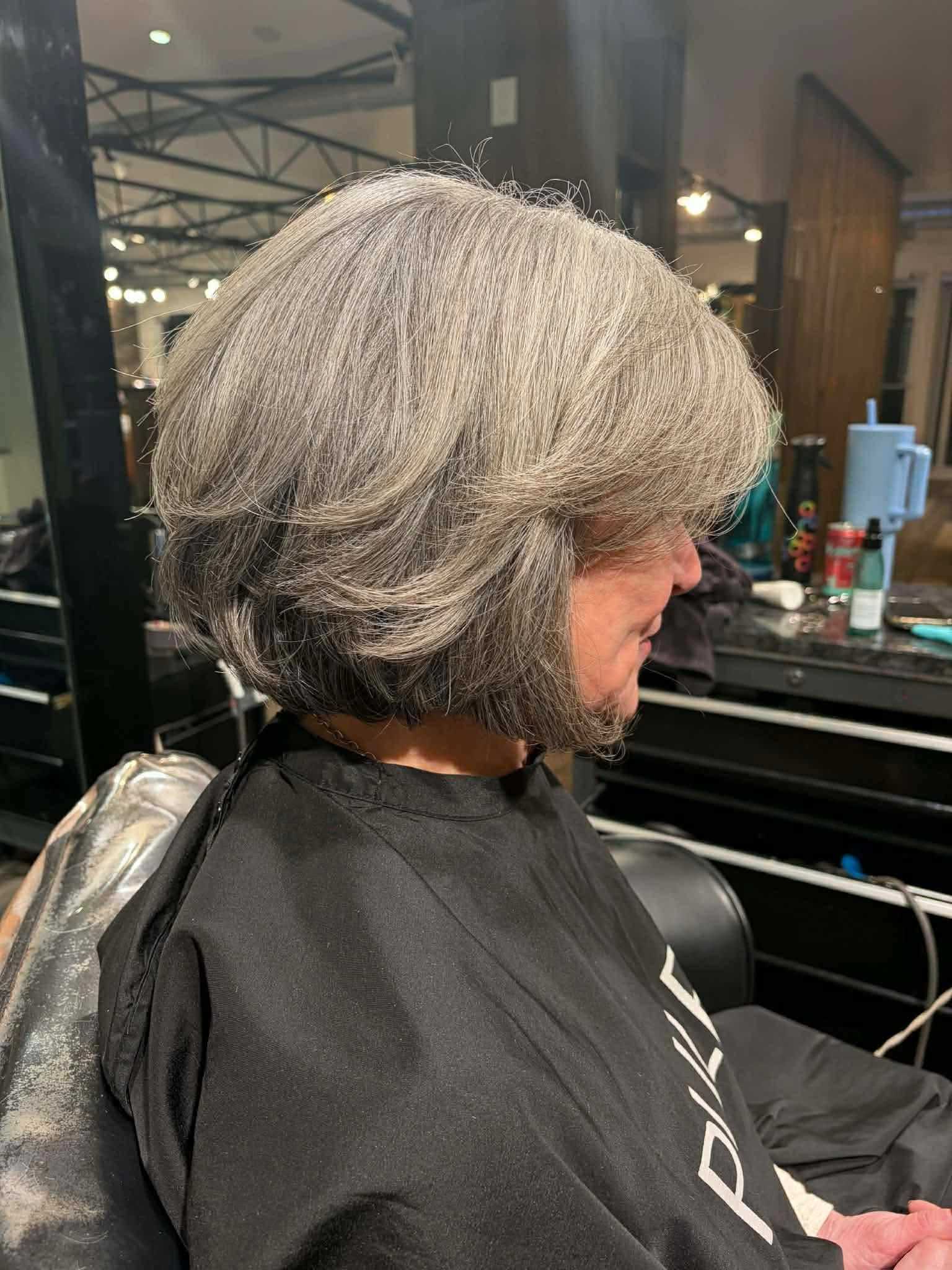 Short gray bob haircut with layers in a salon setting.
